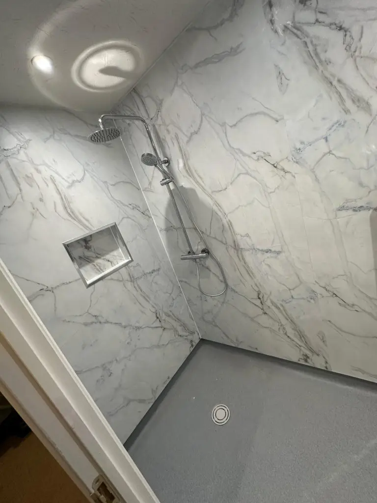 A wet room, with shower, and a recess in the wall for storage.